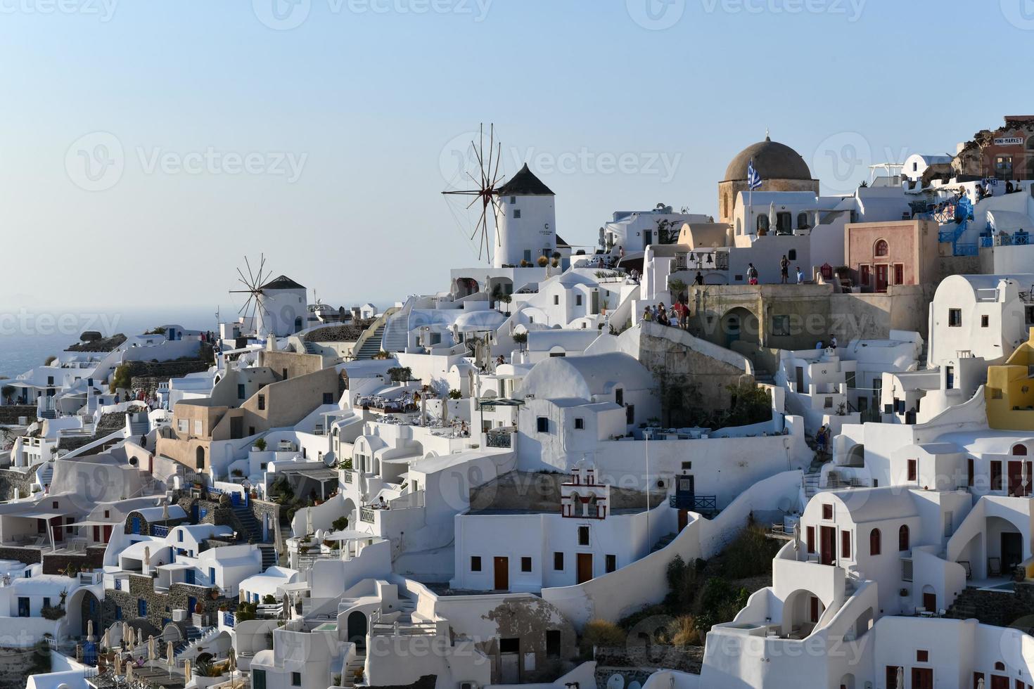 Oia, Greece - Jul 23, 2021, Charming view Oia village on Santorini island, Greece. Traditional famous blue dome church over the Caldera in Aegean sea. Traditional blue and white Cyclades architecture. photo