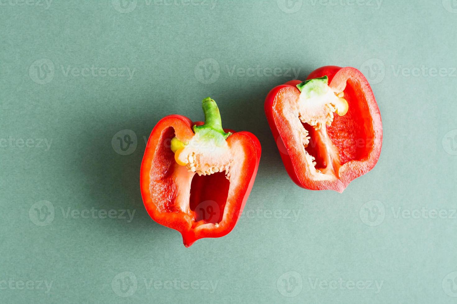Ripe fresh red bell pepper cut in half on a green background. Vegetarian food. Top view. photo