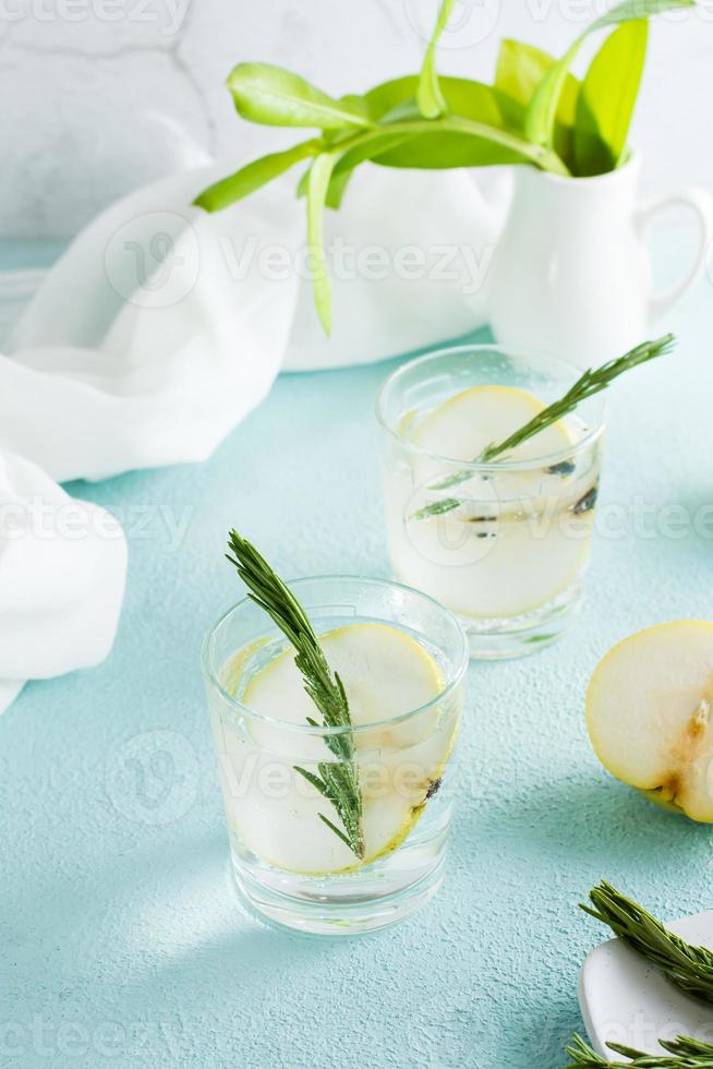 Refreshing cocktail of mineral water and pear slices in glasses on the table. Homemade drinks. Vertical view photo