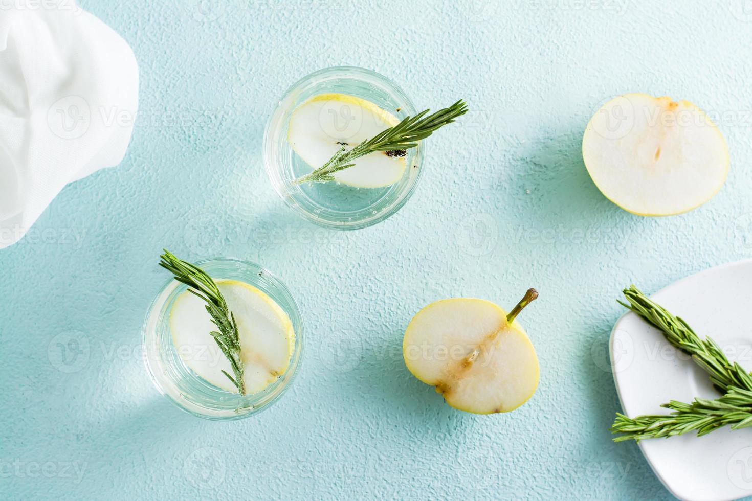 Refreshing cocktail of mineral water and pear slices in glasses on the table. Homemade drinks. Top view photo