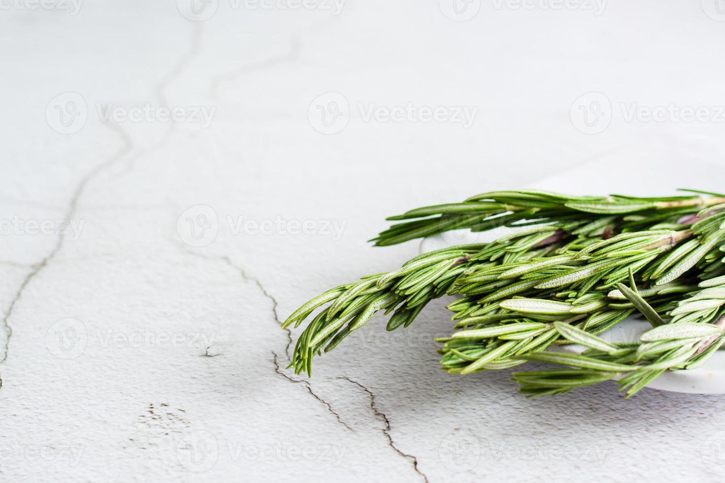 Sprigs of fresh rosemary on a plate on the table. Organic aromatic herb for cooking and health. photo