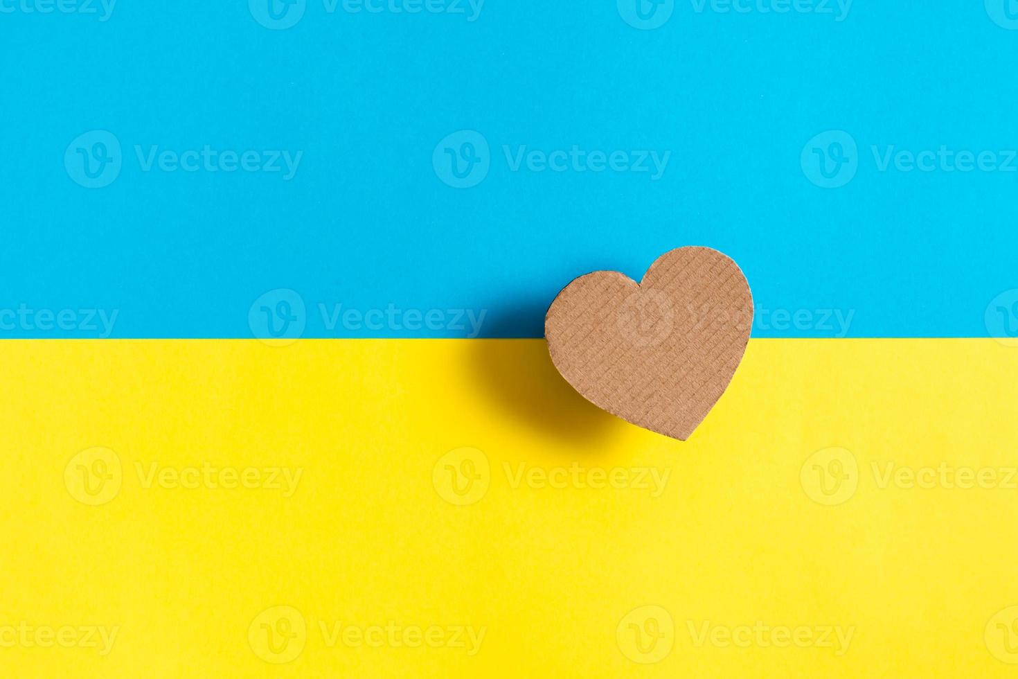 The concept is no war in Ukraine. Cardboard heart on the background of the Ukrainian flag. Top view. photo