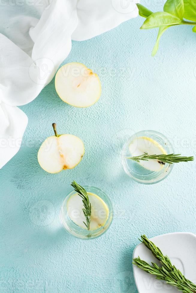 Cold cocktail of pear slices and mineral water in glasses on the table. Homemade drinks. Top and vertical view photo