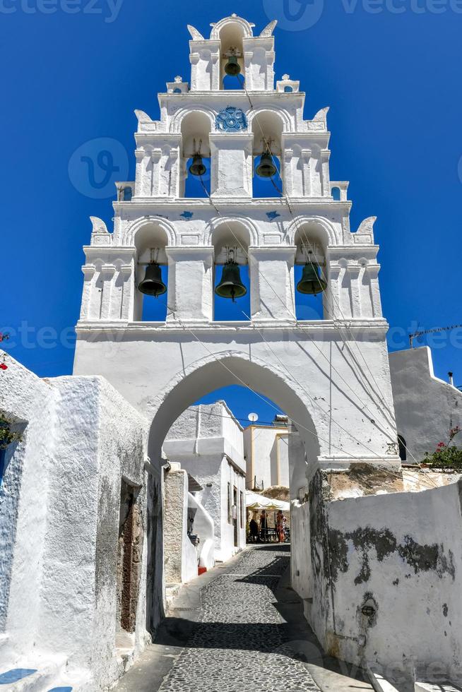 A typical cobblestone street with an arched bell tower in the traditional village of Megalochori in Santorini, Greece. photo