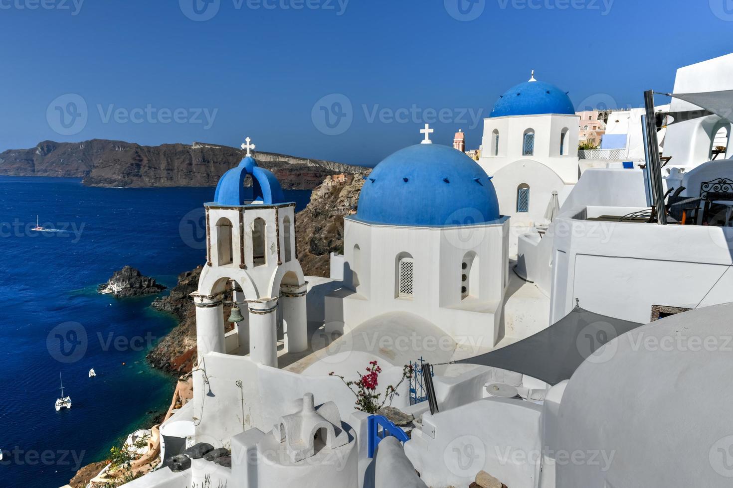 Charming view Oia village on Santorini island, Greece. Traditional famous blue dome church over the Caldera in Aegean sea. Traditional blue and white Cyclades architecture. photo