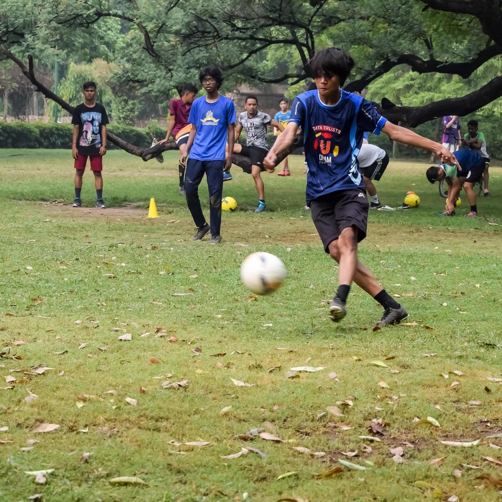 New Delhi, India, July 01 2018 - Footballers of local football team during game in regional Derby championship on a bad football pitch. Hot moment of football match on grass green field of the stadium photo