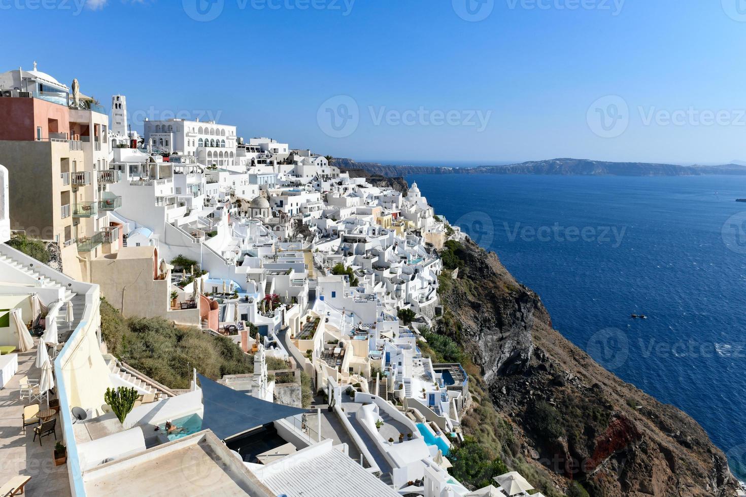 Charming view Fira village on Santorini island, Greece. Traditional famous blue dome church over the Caldera in Aegean sea. Traditional blue and white Cyclades architecture. photo