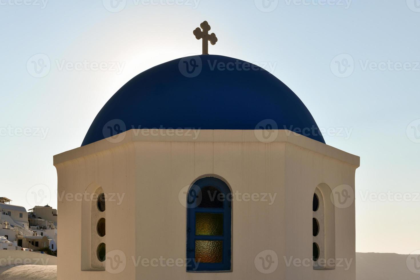 Charming view Oia village on Santorini island, Greece. Traditional famous blue dome church over the Caldera in Aegean sea. Traditional blue and white Cyclades architecture. photo