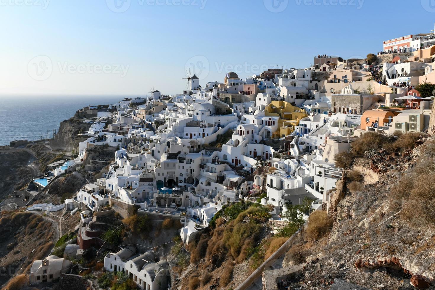 Oia, Greece - Jul 23, 2021, Charming view Oia village on Santorini island, Greece. Traditional famous blue dome church over the Caldera in Aegean sea. Traditional blue and white Cyclades architecture. photo
