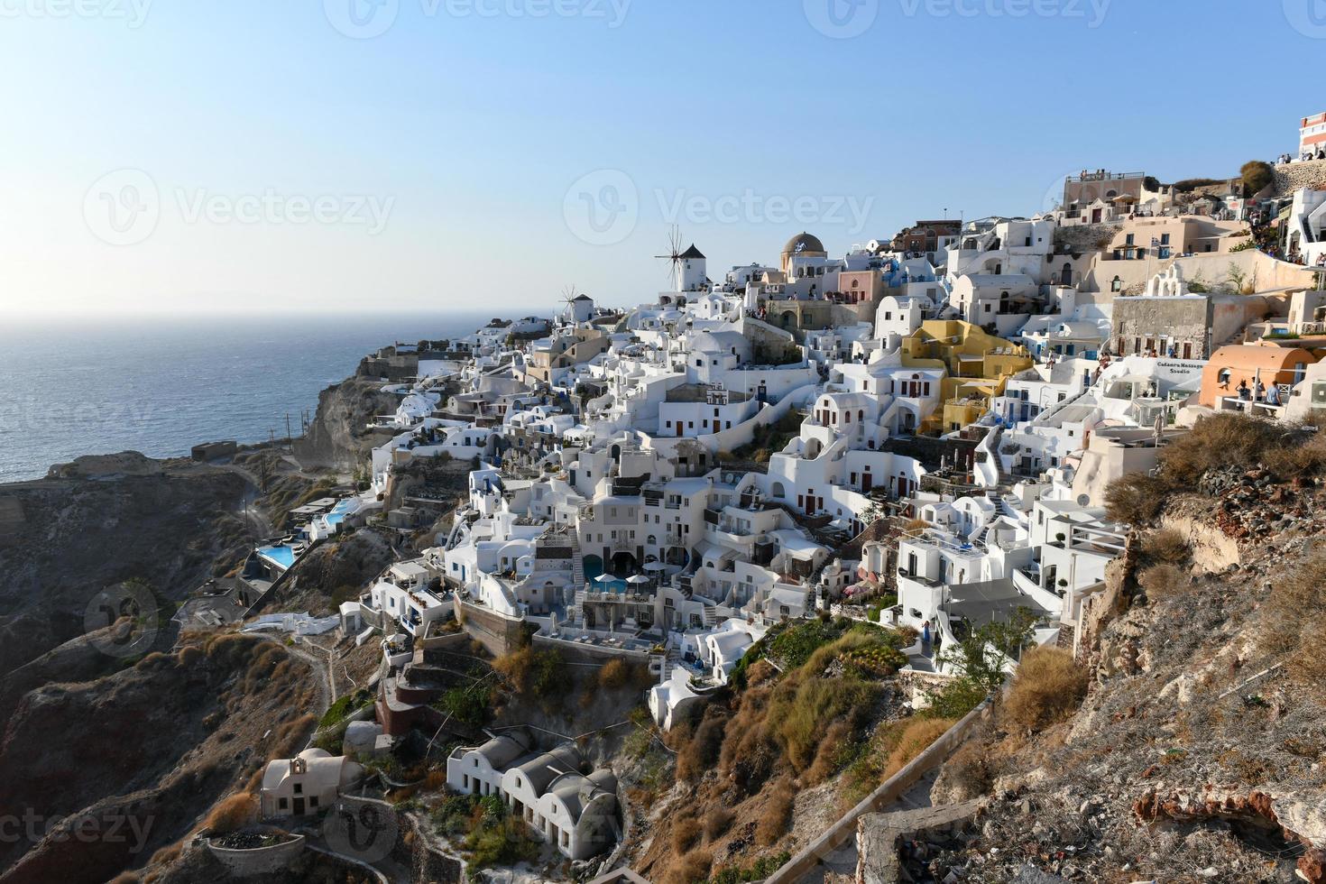 Charming view Oia village on Santorini island, Greece. Traditional famous blue dome church over the Caldera in Aegean sea. Traditional blue and white Cyclades architecture. photo