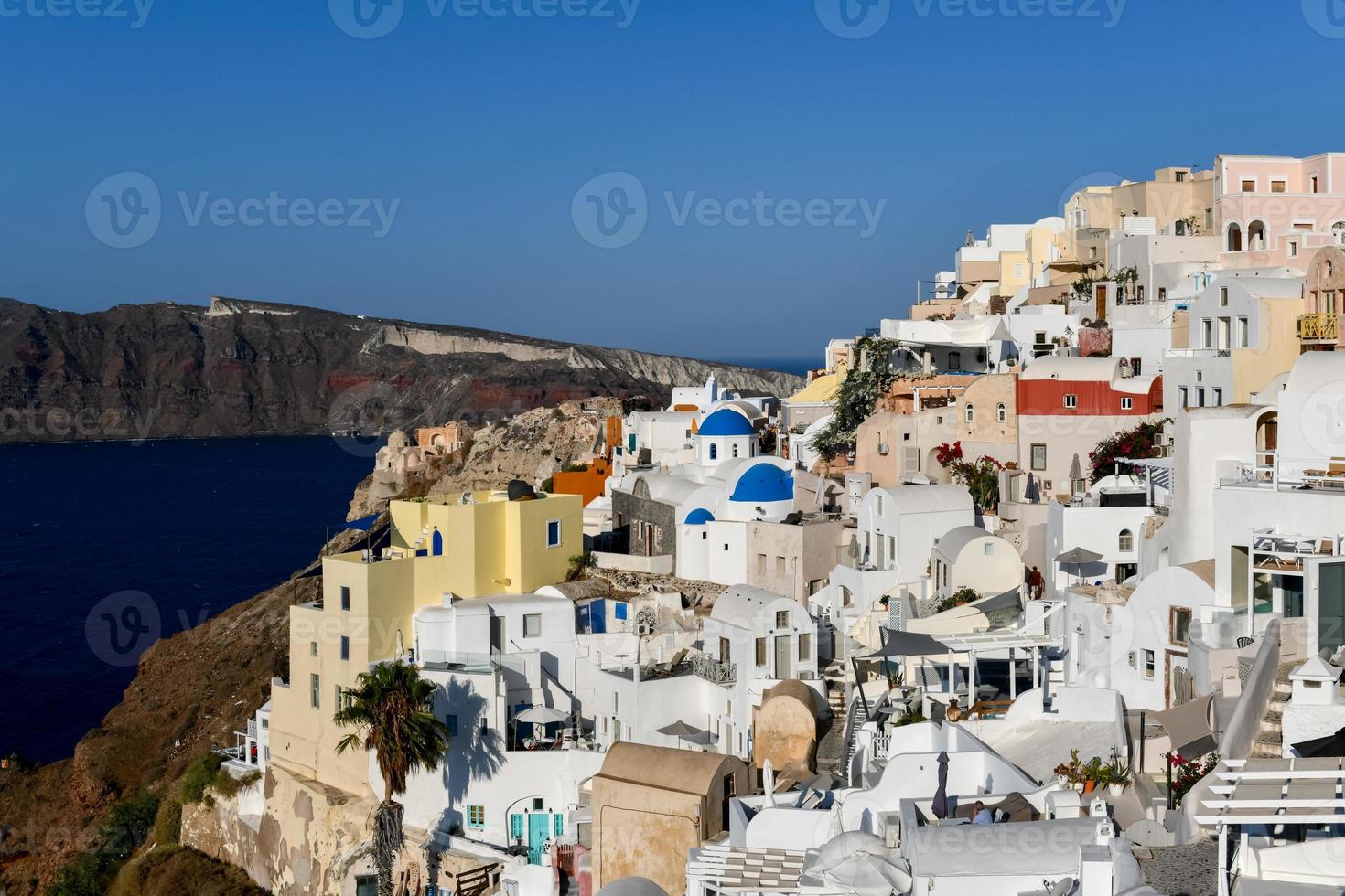 Charming view Oia village on Santorini island, Greece. Traditional famous blue dome church over the Caldera in Aegean sea. Traditional blue and white Cyclades architecture. photo