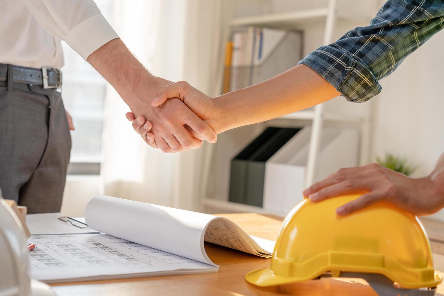 manos del equipo de trabajadores de la construcción agitando el plan de inicio de saludo nuevo contrato de proyecto en el centro de oficinas en el sitio de construcción, industria, arquitectura, socio, trabajo en equipo, acuerdo, propiedad, contactos. foto