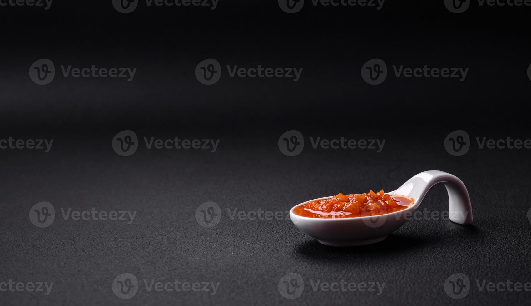 Red adjika sauce or ketchup with spices and herbs photo