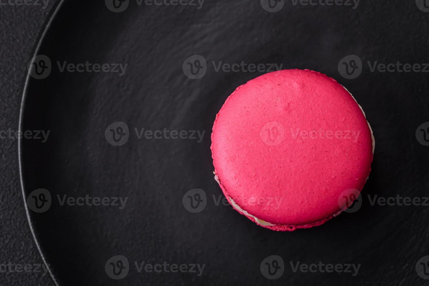 Beautiful tasty macaron with filling and fruit flavor on a black plate photo
