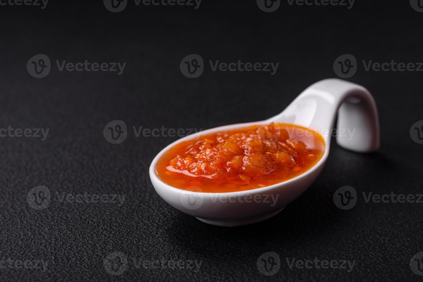 Red adjika sauce or ketchup with spices and herbs photo