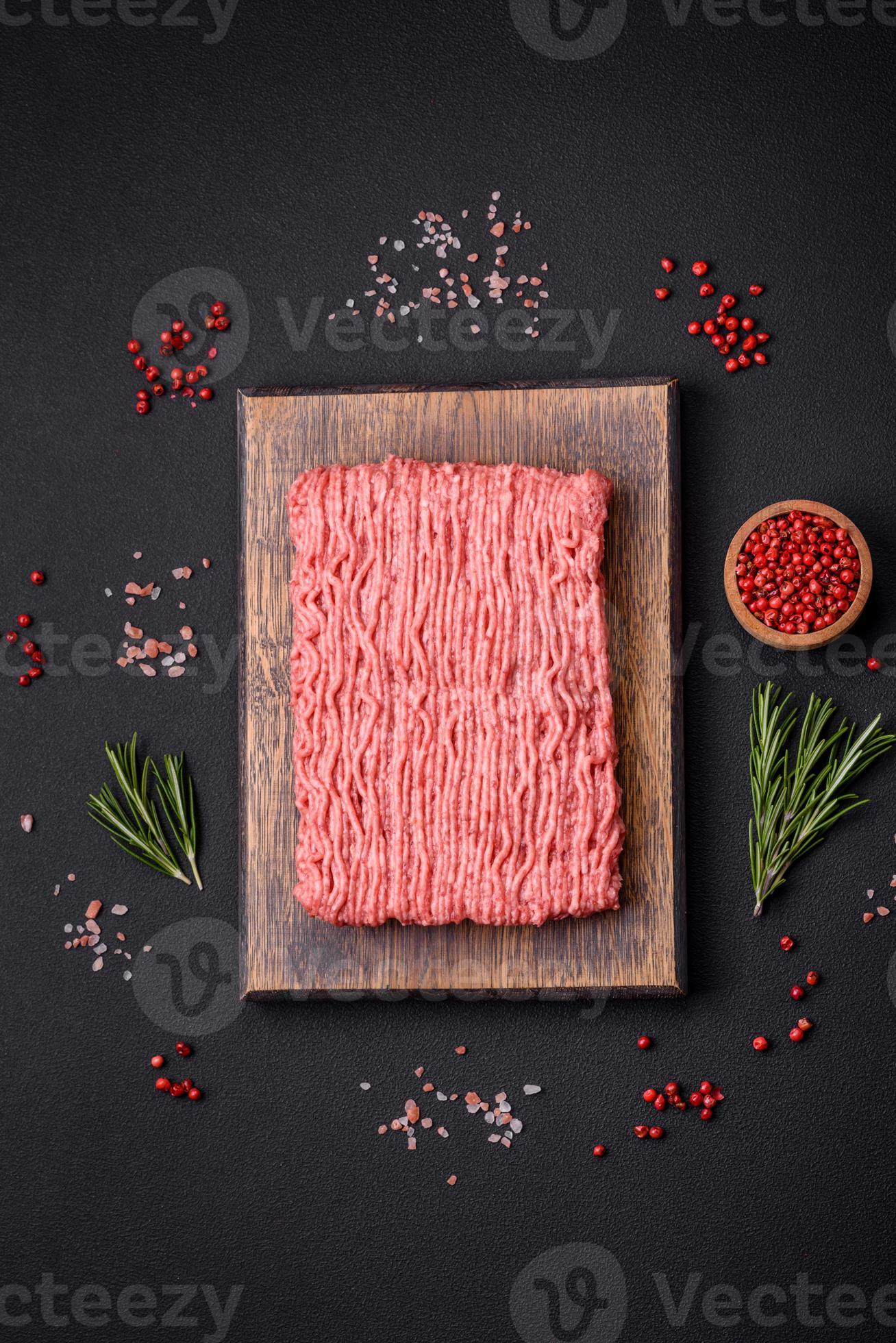 Raw Beef Or Pork Mince With Salt Spices And Herbs On A Wooden Cutting raw-beef-or-pork-mince-with-salt-spices-and-herbs-on-a-wooden-cutting