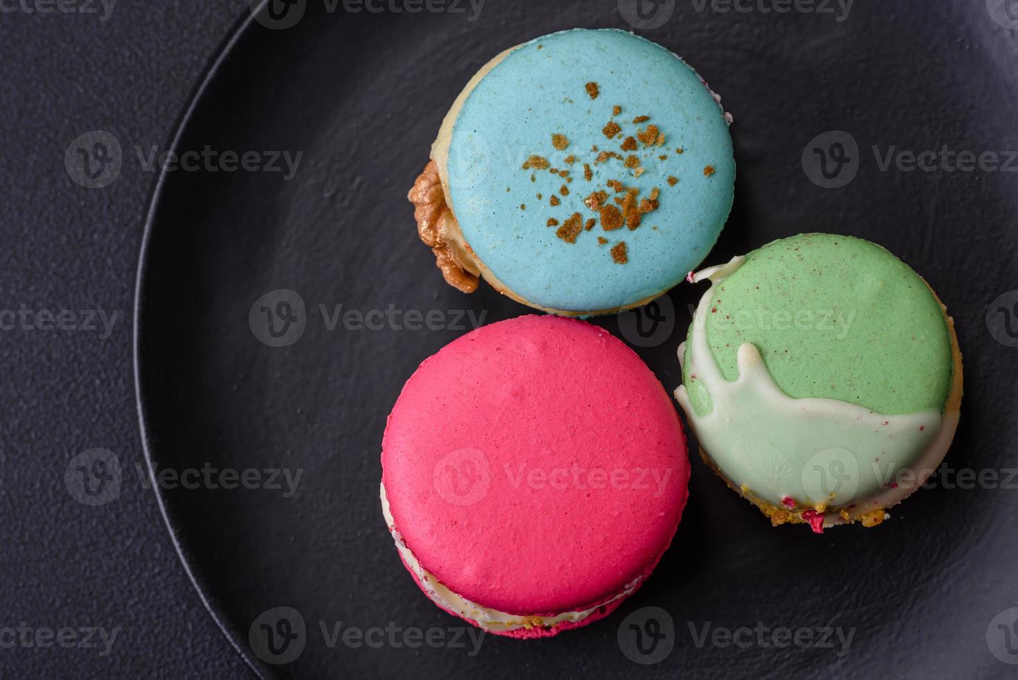 hermosa sabroso macaron con relleno y Fruta sabor en un negro plato foto