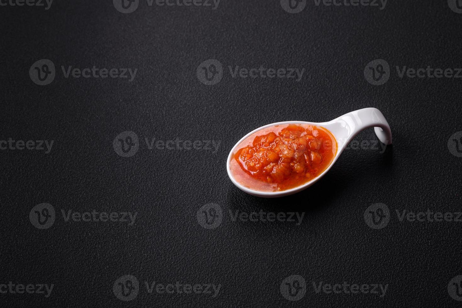 Red adjika sauce or ketchup with spices and herbs photo