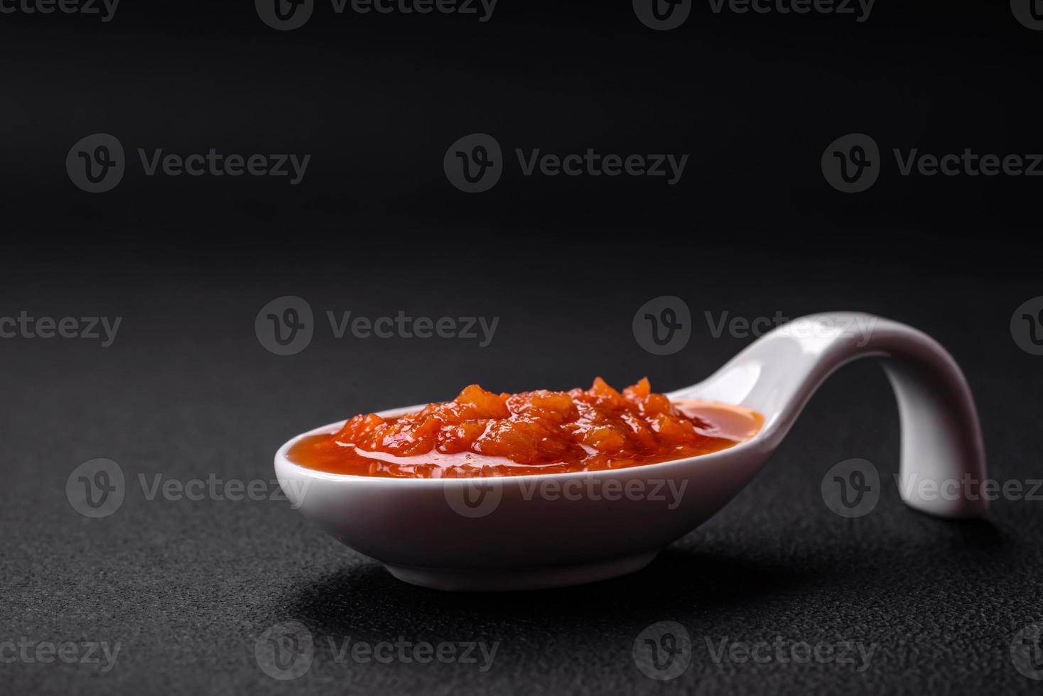 Red adjika sauce or ketchup with spices and herbs photo