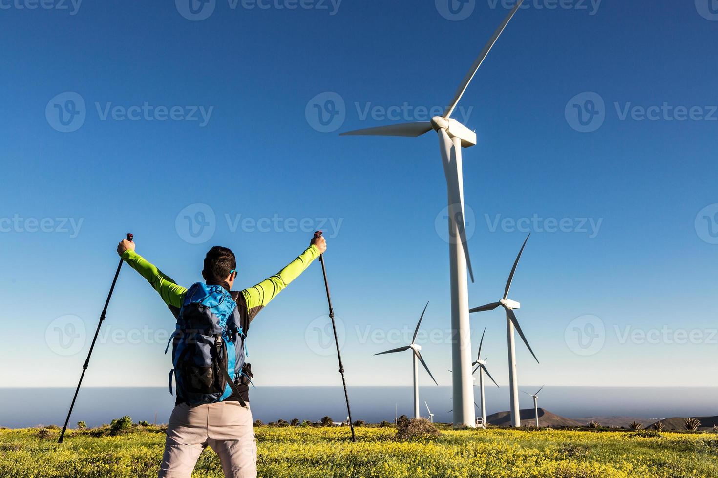 Male discoverer celebrating victory in meadow with windmills photo