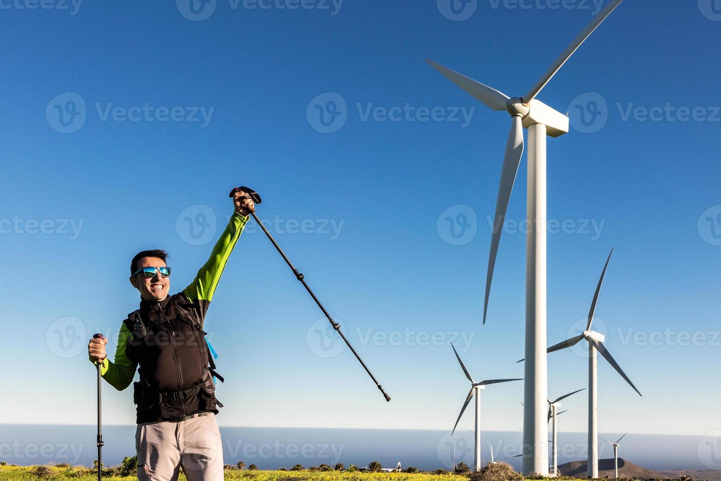 Cheerful traveler celebrating victory in field with windmills photo