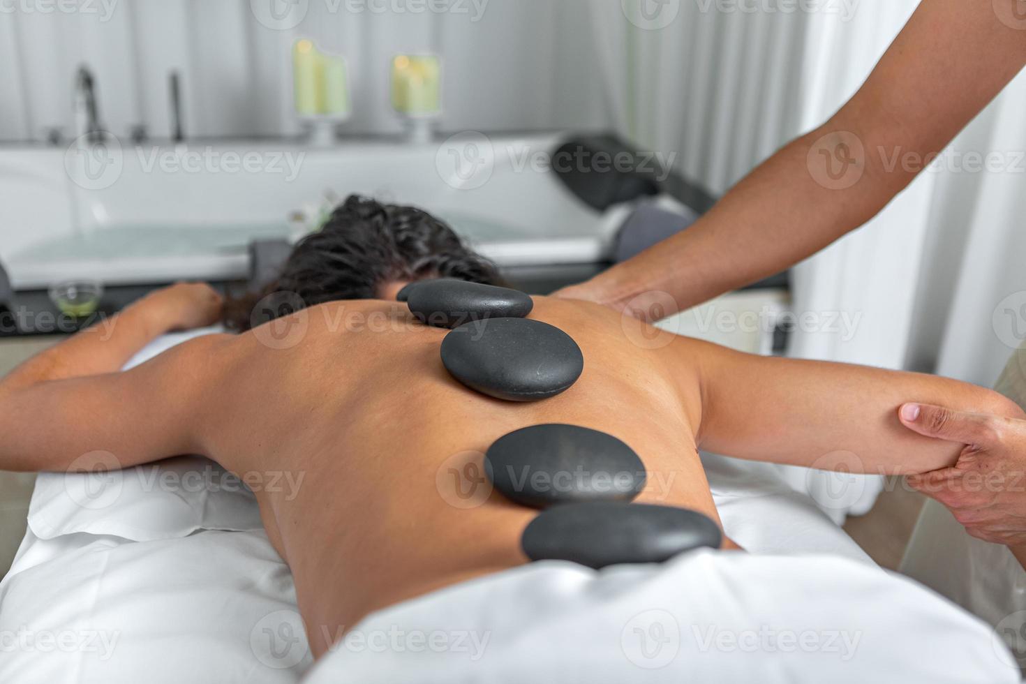 https://static.vecteezy.com/system/resources/previews/019/987/052/non_2x/close-rear-view-of-a-woman-having-hot-stone-massage-in-spa-salon-while-getting-an-arm-and-shoulder-massage-photo.jpg