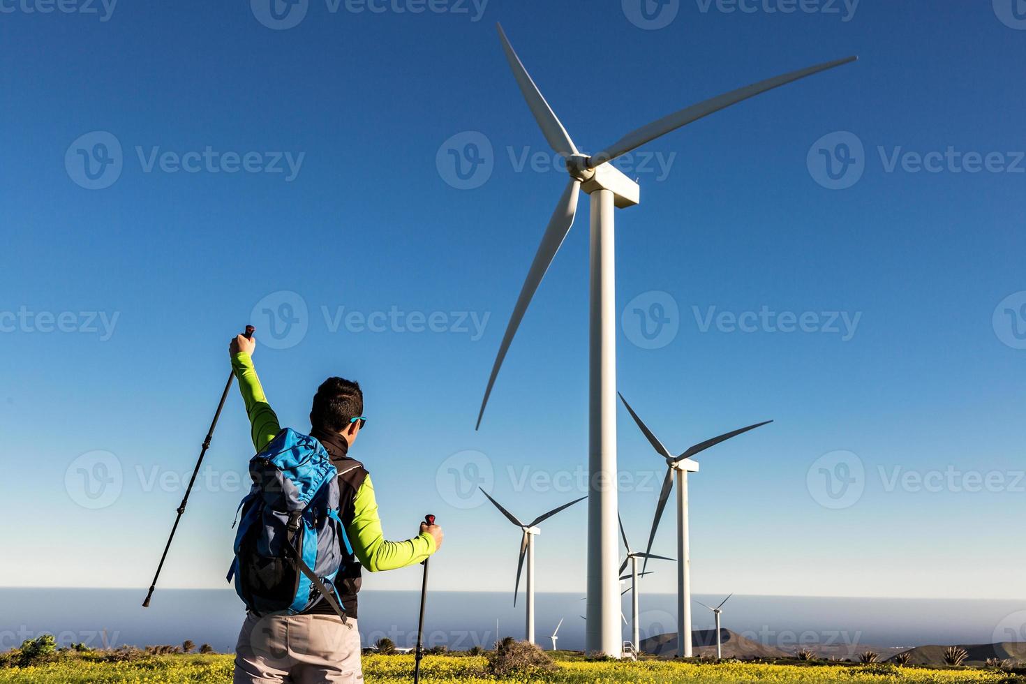 Traveling man with raised hand in field with windmills photo