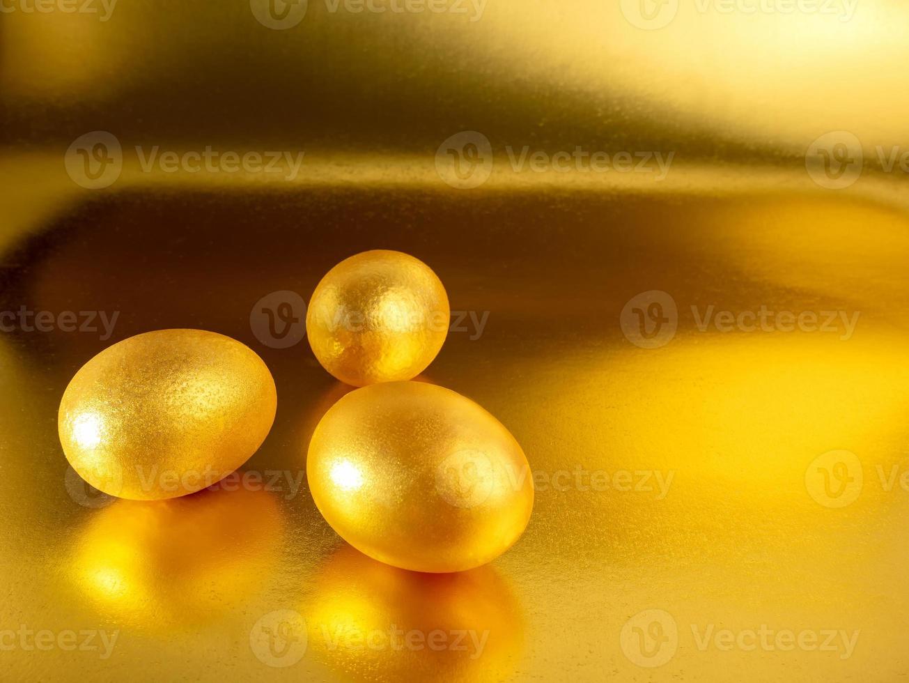 Three easter eggs painted in gold on a glittering background for the holiday of bright easter. photo