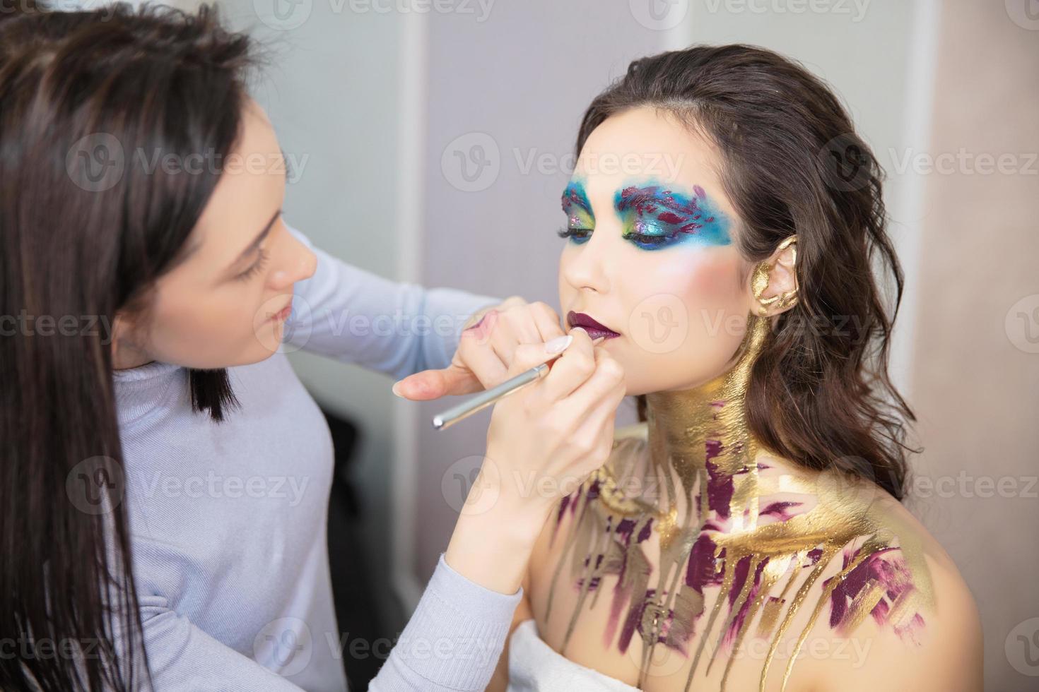 The artist applies makeup to a pretty young model photo