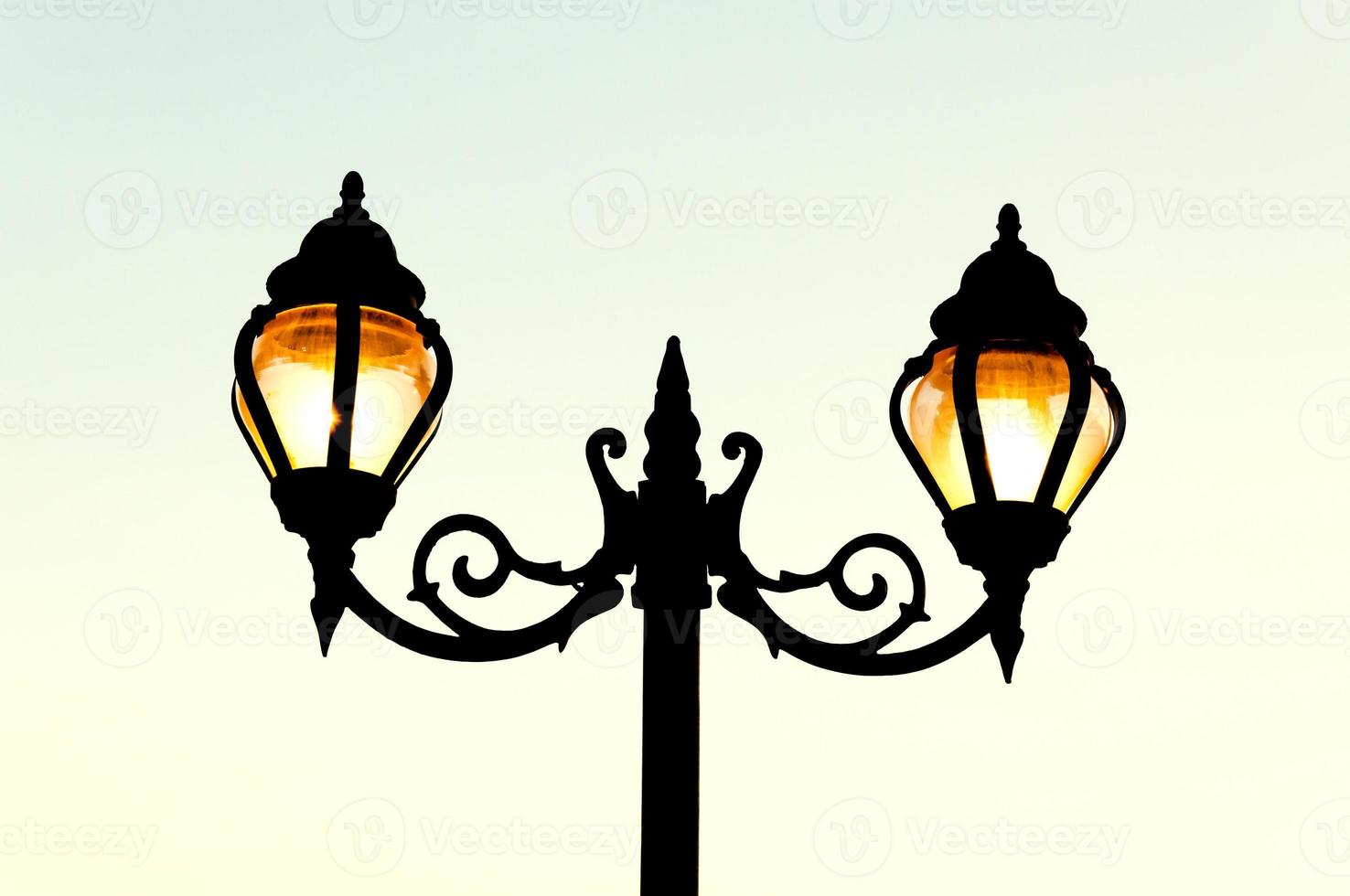 Beautiful vintage Street antique style lamp post with effect of shine from low light of sunset photo