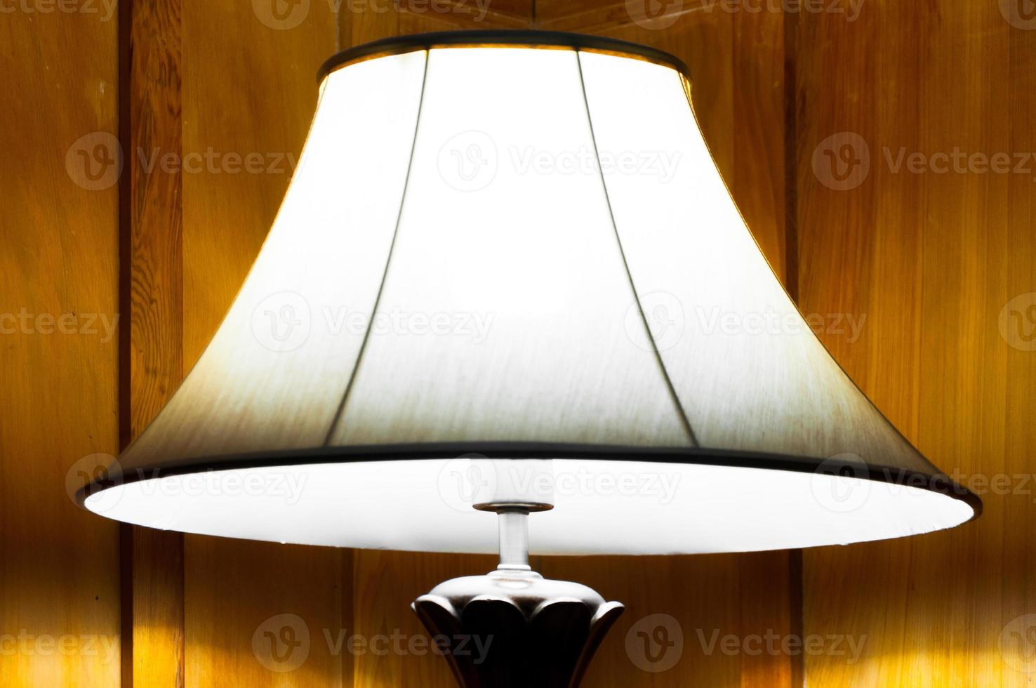 Elegant lamp in warm interior room,Turned On Old Lamp near the wooden wall photo