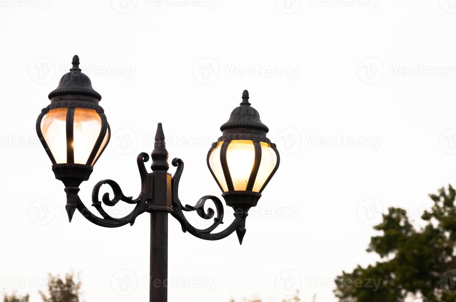 Beautiful vintage Street antique style lamp post with effect of shine from low light of sunset photo