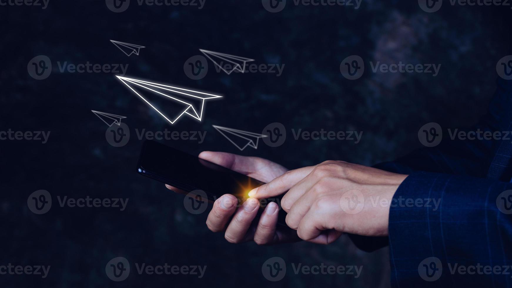 Businessman holding smartphone Paper airplane takes off from a smartphone, the concept of communication and message forwarding,future connection concept, telecommunication photo
