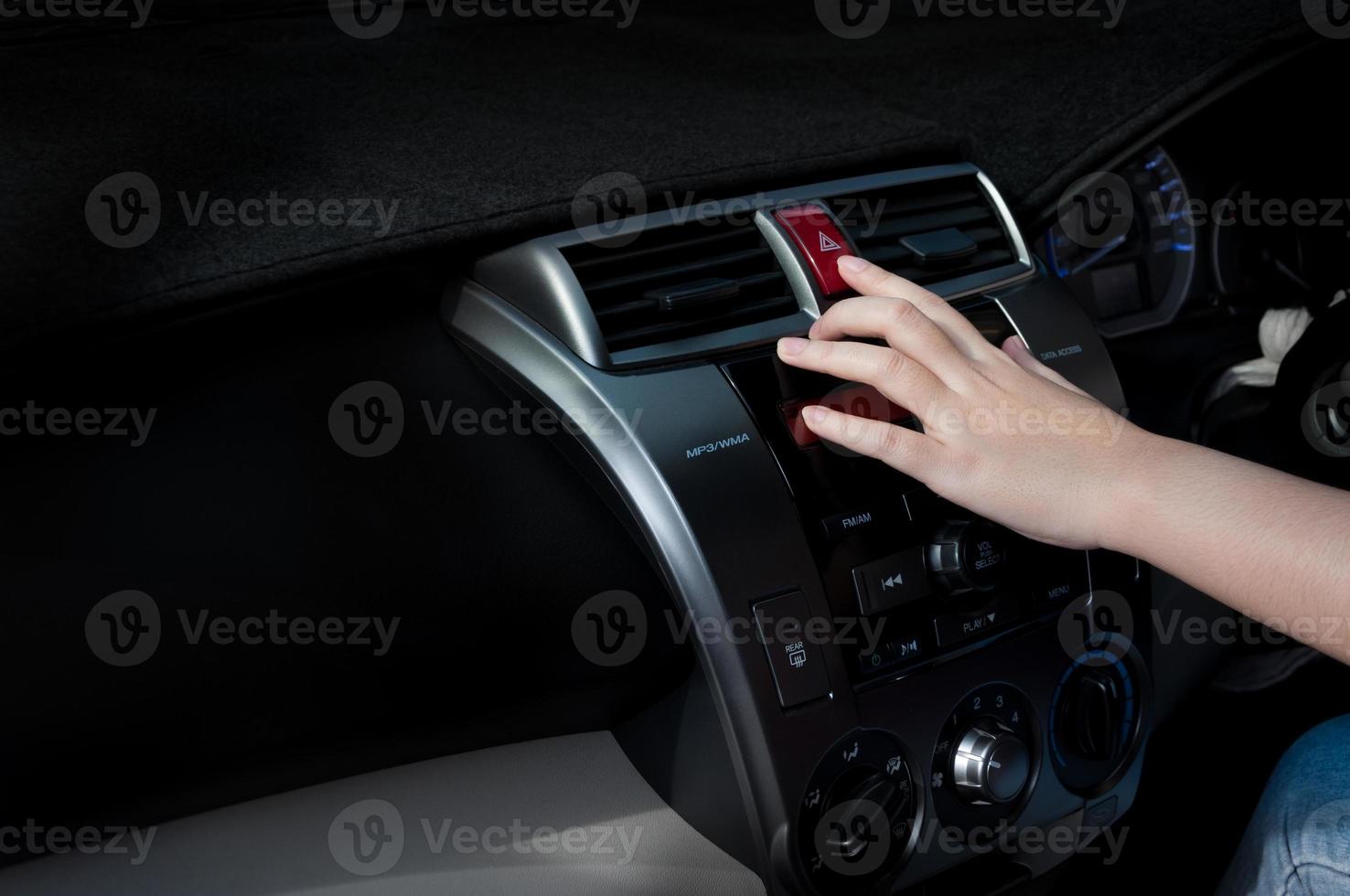 woman finger pressing car emergency light button in car photo