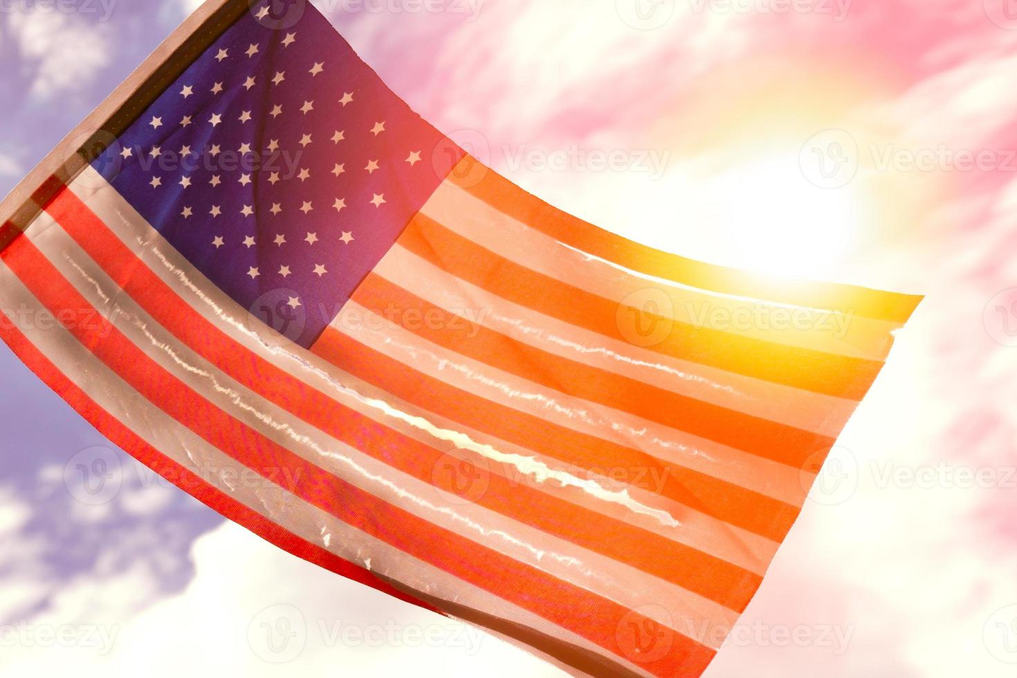 Old American flag dilapidated perforated burned grunge tattered by golden sunset light photo