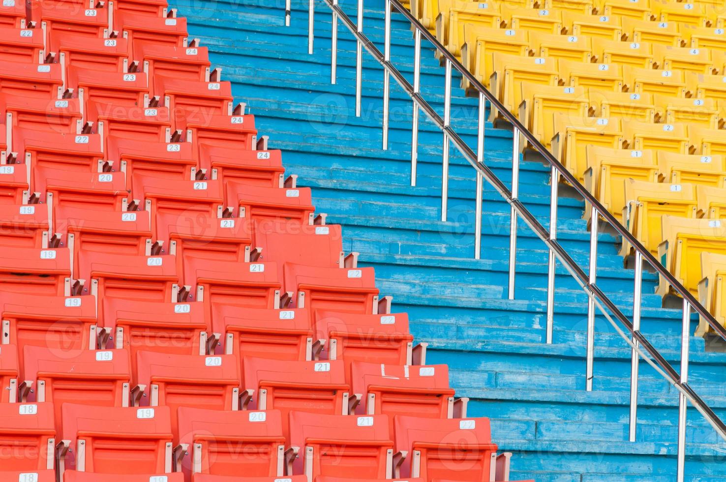 asientos vacíos de color naranja y amarillo en el estadio, filas de asientos en un estadio de fútbol foto