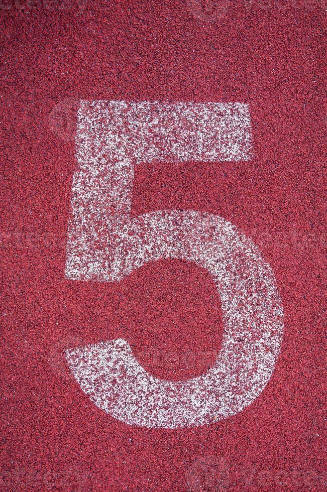 Number five on running track. White track number on red rubber racetrack, texture of running racetracks in stadium photo