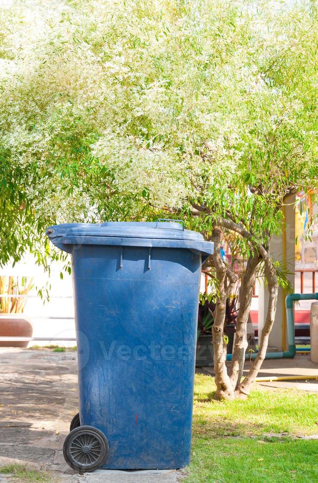 dirty old blue bin with wheel  in the park photo