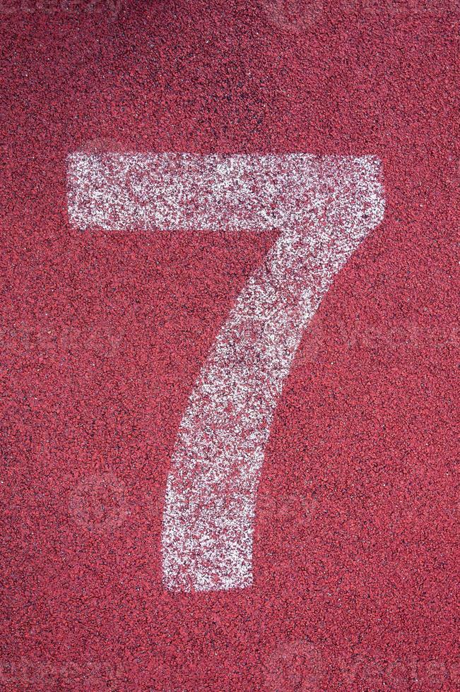 Number seven on running track. White track number on red rubber racetrack, texture of running racetracks in stadium photo