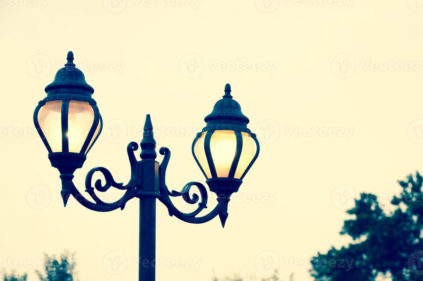 Beautiful vintage Street antique style lamp post with effect of shine from low light of sunset photo