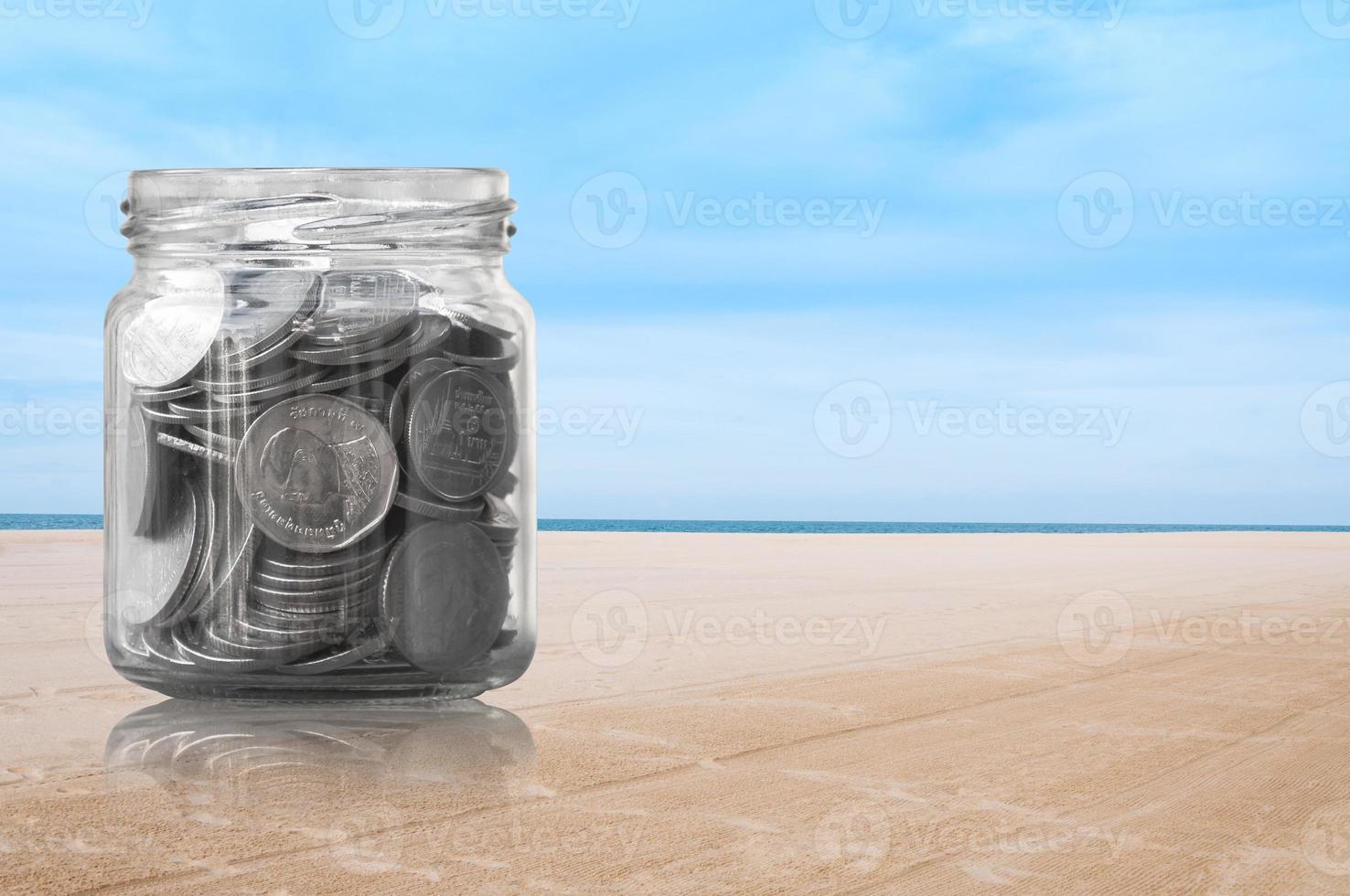 Coins in a glass jar on beach nature background ,savings coins - Investment And Interest Concept saving money concept photo