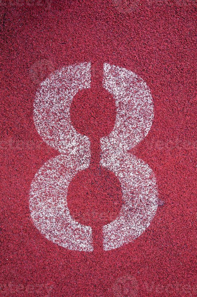 Number eight on running track. White track number on red rubber racetrack, texture of running racetracks in stadium photo