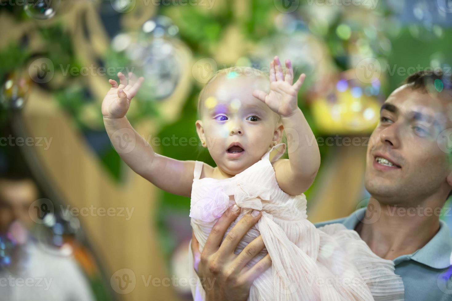 Dad's Day. Dad plays with his little daughter on the background of soap bubbles. photo