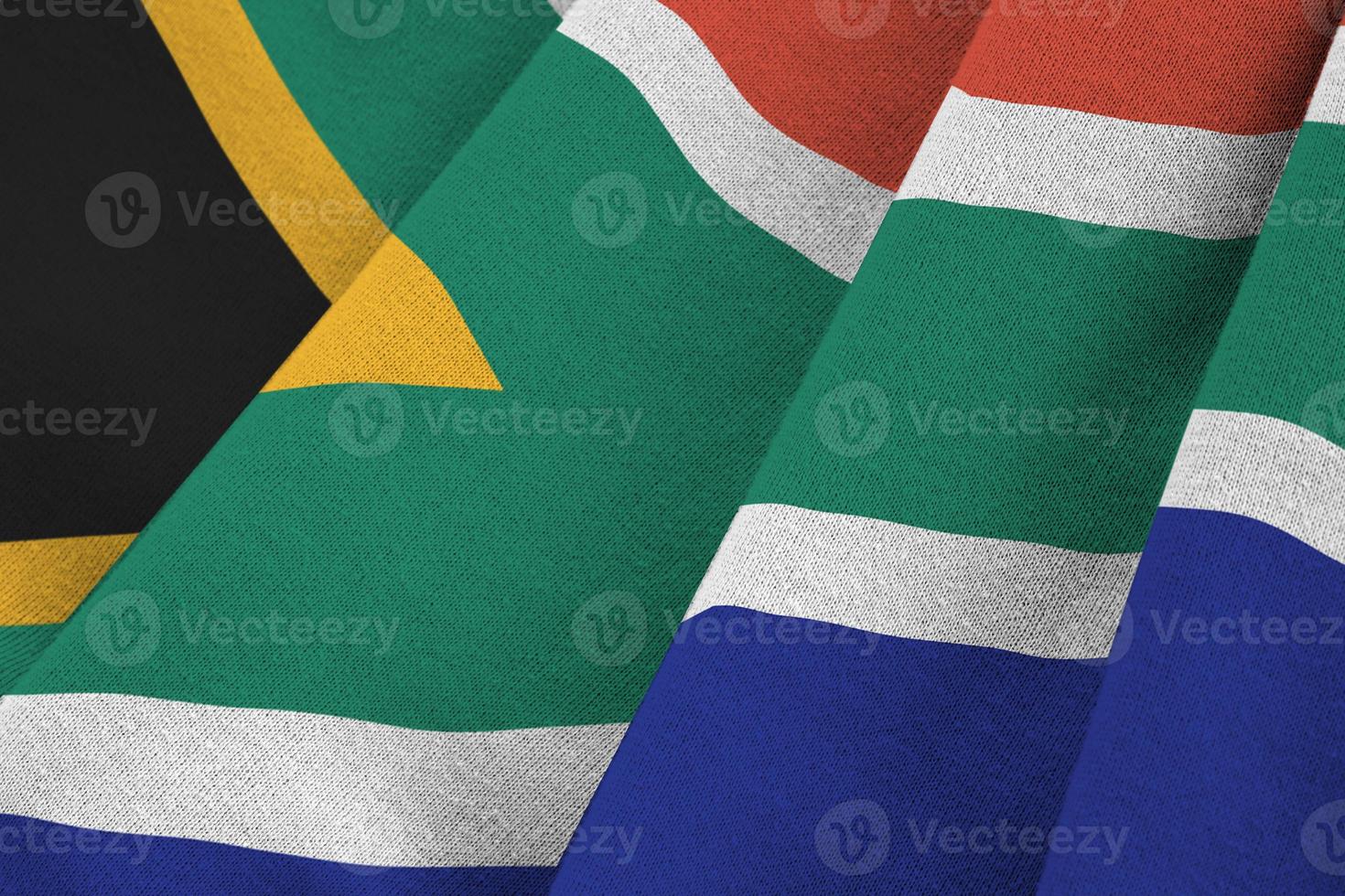 South Africa flag with big folds waving close up under the studio light indoors. The official symbols and colors in banner photo
