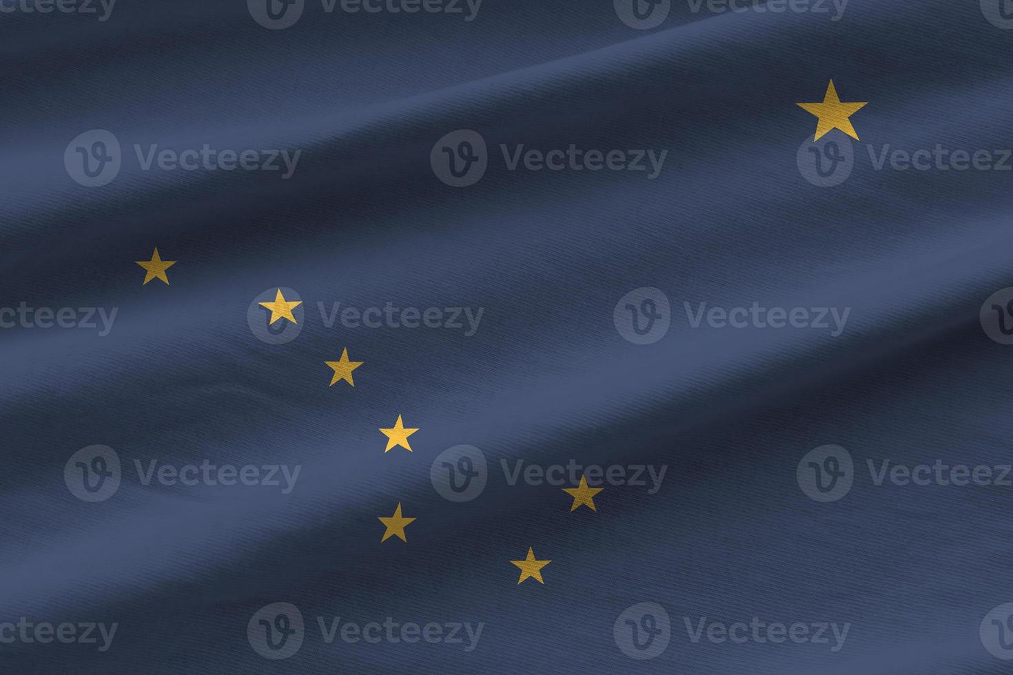 Alaska US state flag with big folds waving close up under the studio light indoors. The official symbols and colors in banner photo