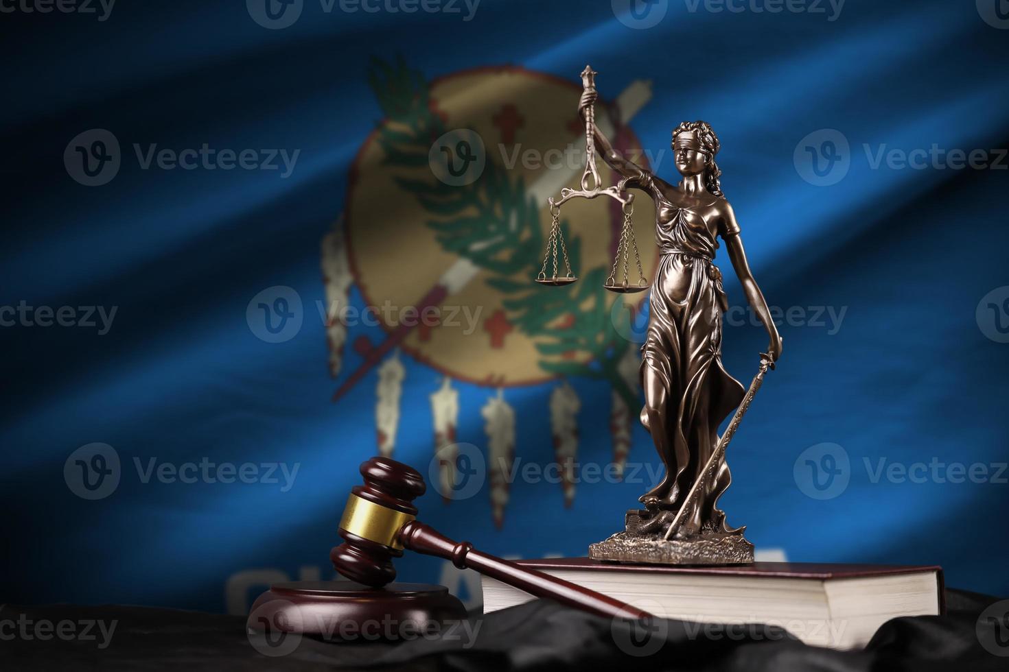 Oklahoma US state flag with statue of lady justice, constitution and judge hammer on black drapery. Concept of judgement and guilt photo