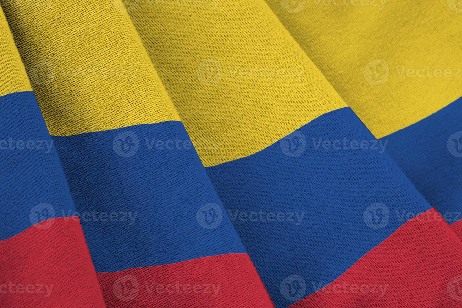 Colombia flag with big folds waving close up under the studio light indoors. The official symbols and colors in banner photo