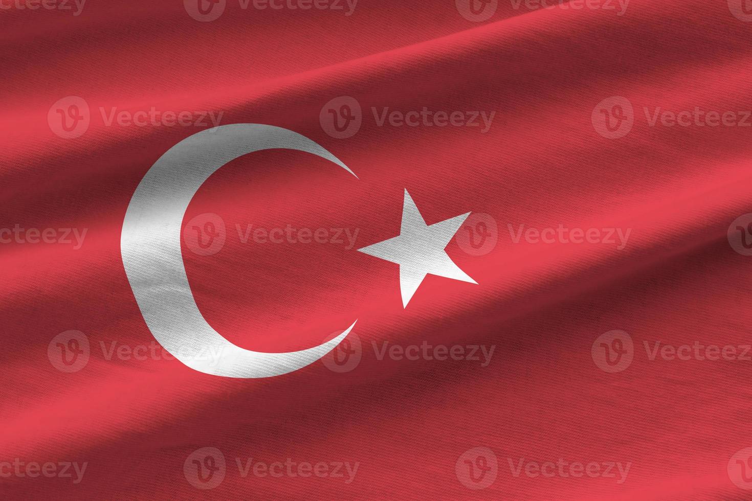 Turkey flag with big folds waving close up under the studio light indoors. The official symbols and colors in banner photo