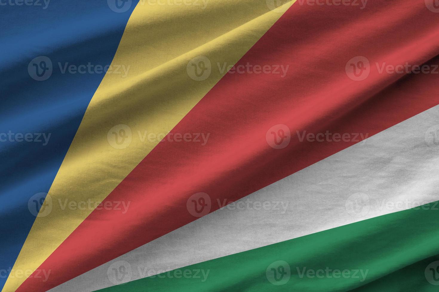 Seychelles flag with big folds waving close up under the studio light indoors. The official symbols and colors in banner photo
