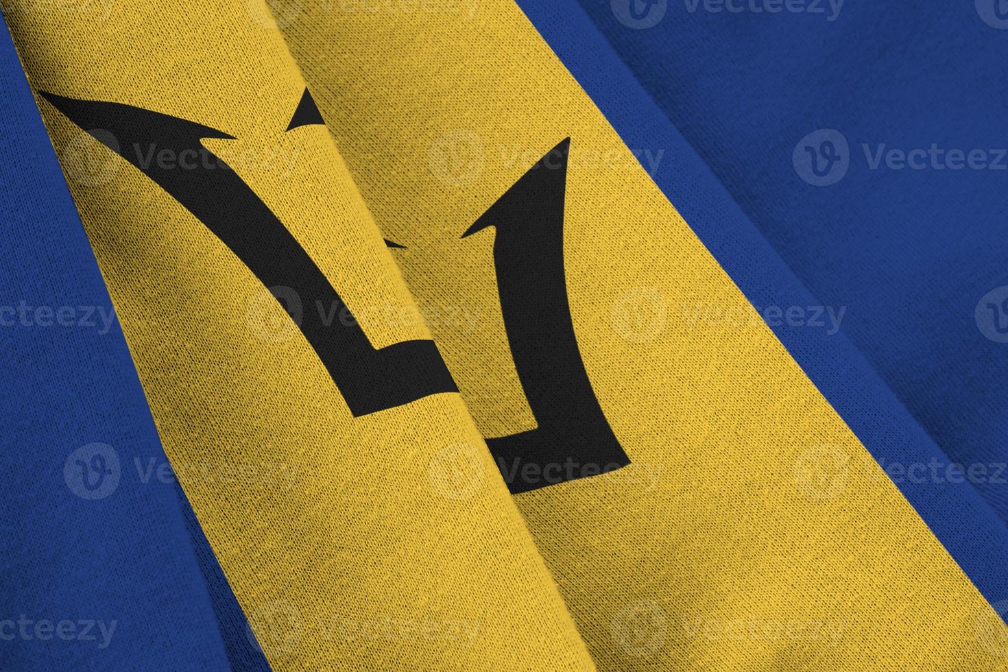 Barbados flag with big folds waving close up under the studio light indoors. The official symbols and colors in banner photo